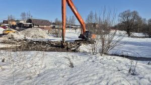 Расчистка реки экскаватором с длинной стрелой от мусора